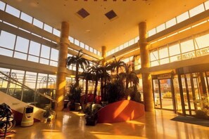 Eine geräumige Lobby mit hohen Decken, großen Fenstern und einer zentralen Treppe.
