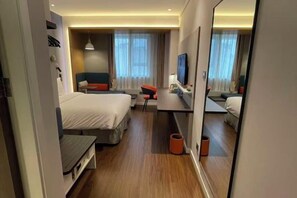 A hotel room with a bed, desk, chair, TV, and a mirror. - Holiday Inn Express TIANJIN DONGLI PLAZA (Tianjin)