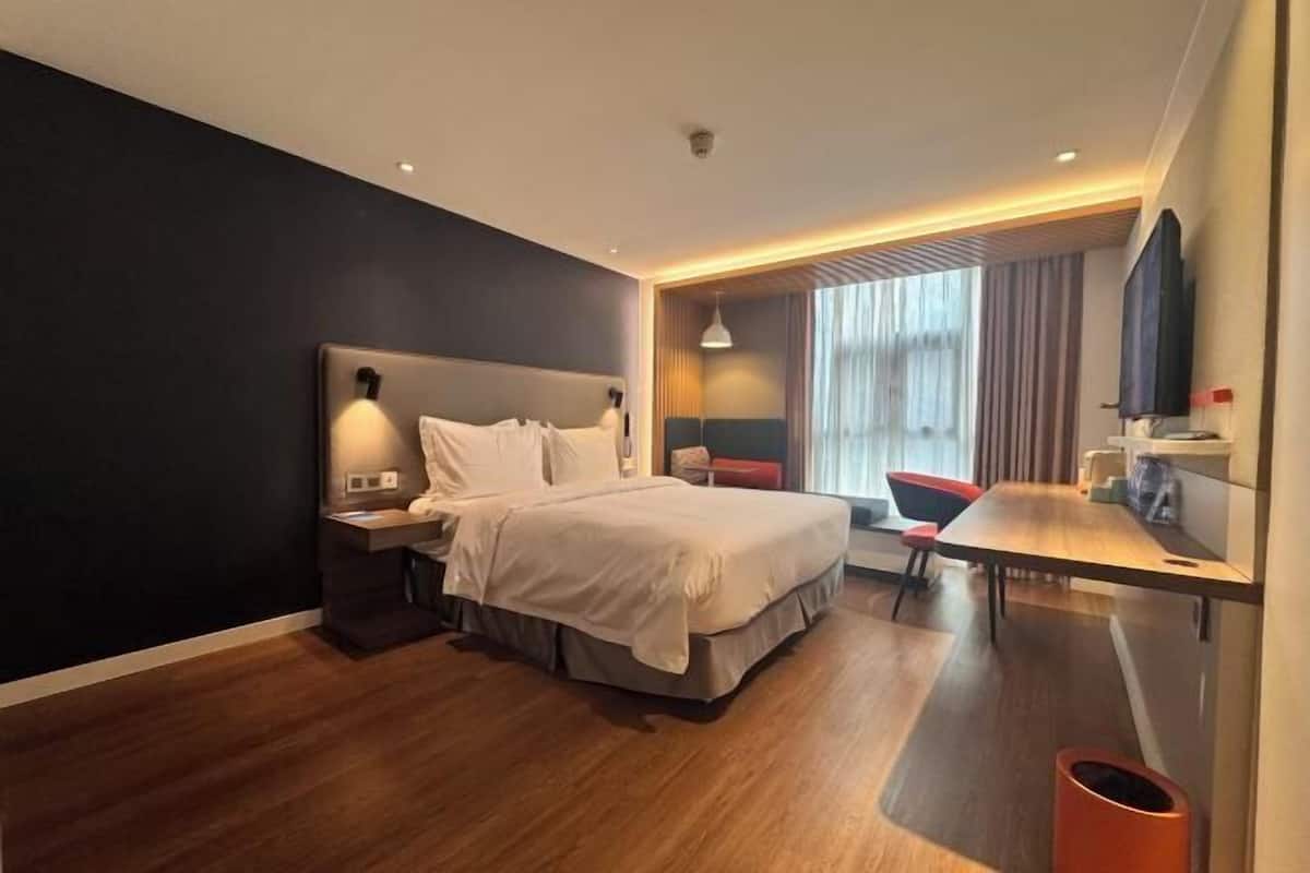 Una habitación de hotel moderna con una cama grande, una mesita de noche y un área de escritorio.