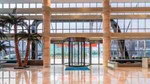 Un hall d’entrée spacieux doté d’une porte tournante, de palmiers et d’un sol ciré.