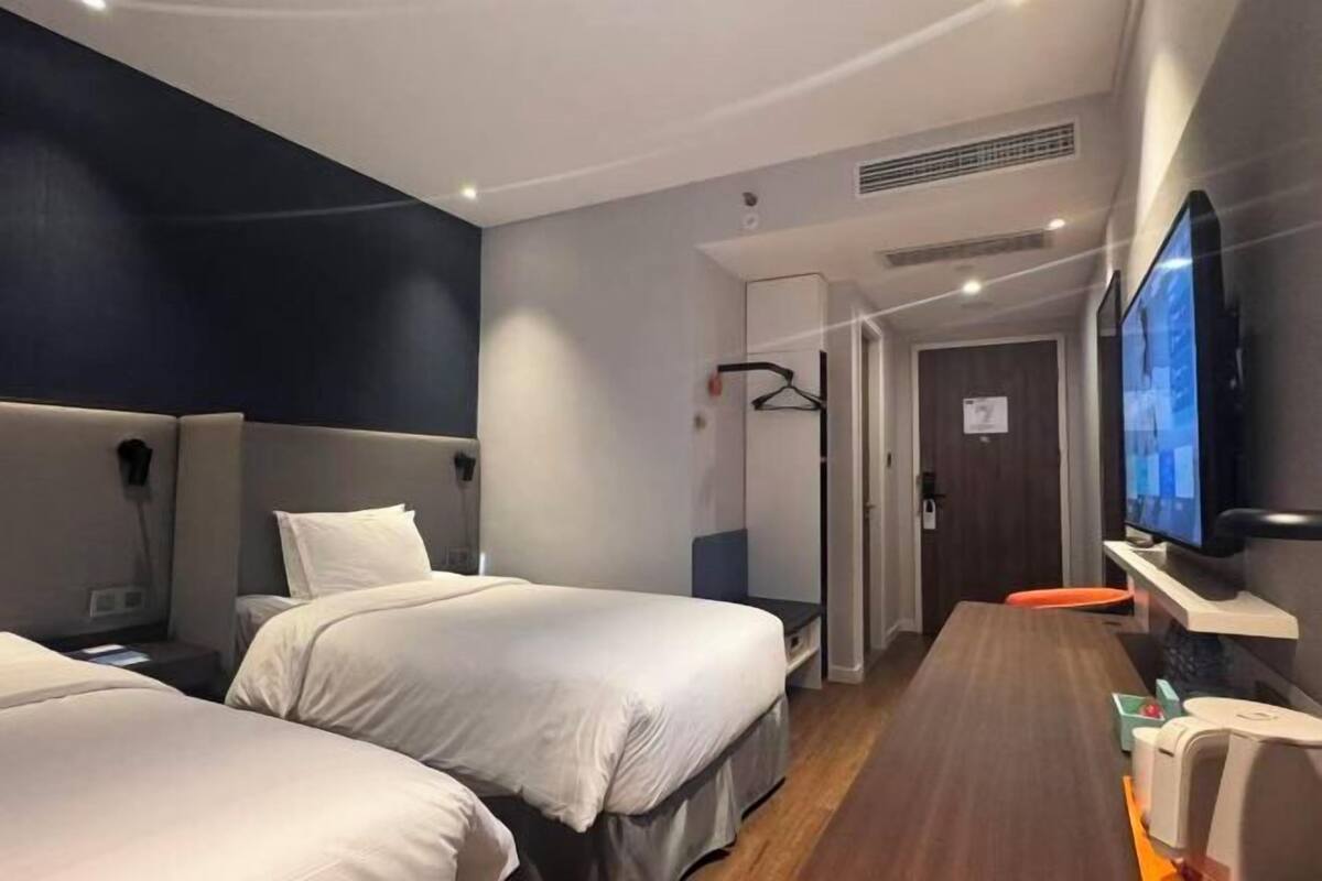 Una habitación de hotel con dos camas, televisión, escritorio y silla.