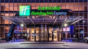 L’entrée d’un hôtel Holiday Inn Express, avec une façade en verre, un panneau lumineux et une porte tournante.