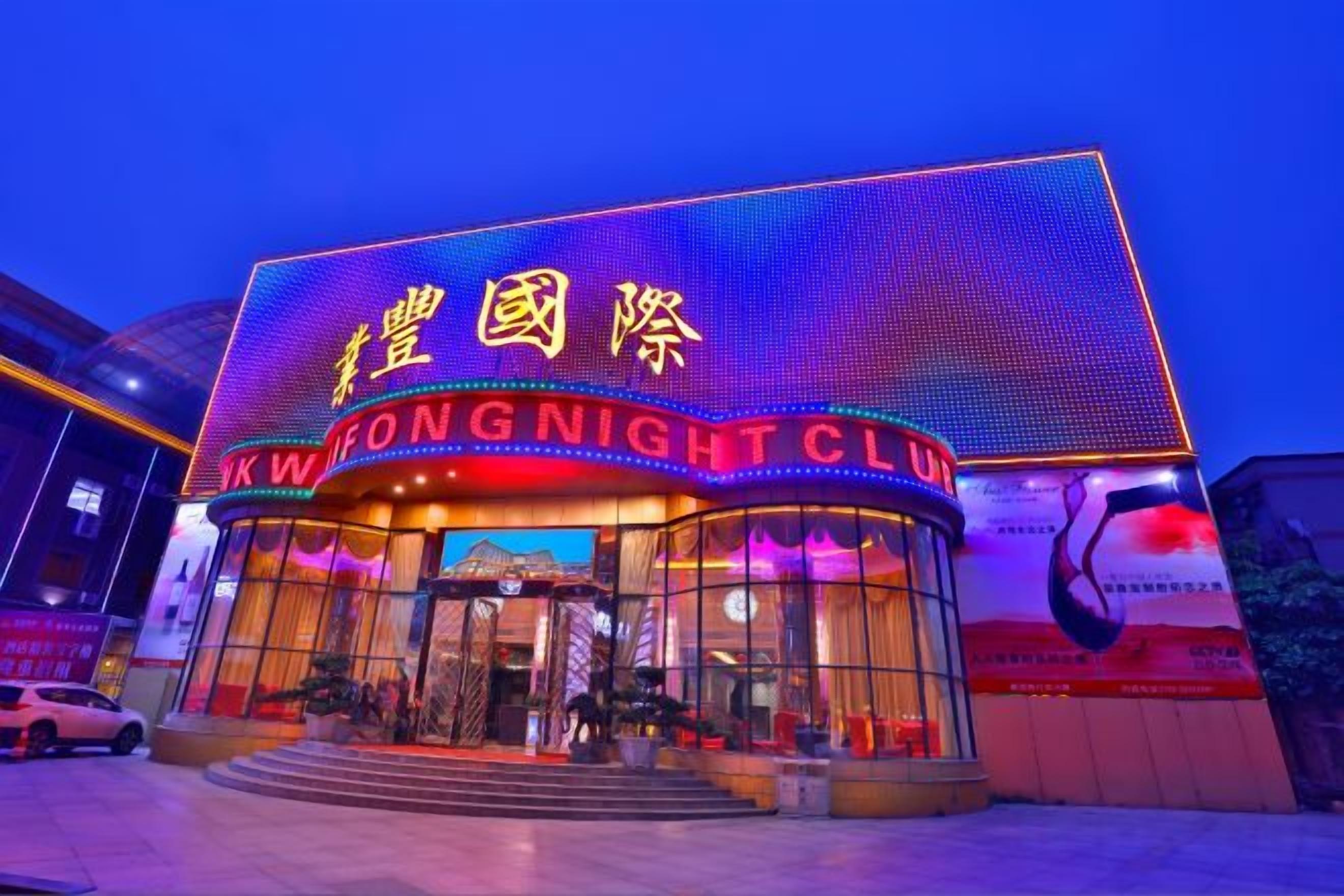 Ein Gebäude mit beleuchteter Schilderung, auf der 'KWONG NIGHT CLUB' und chinesische Schriftzeichen stehen.