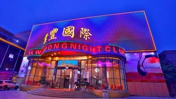 Ein Gebäude mit beleuchteter Schilderung, auf der 'KWONG NIGHT CLUB' und chinesische Schriftzeichen stehen.