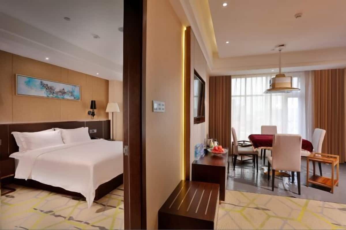 Une chambre d’hôtel comprenant un lit, un bureau et un coin repas avec des chaises et une table.