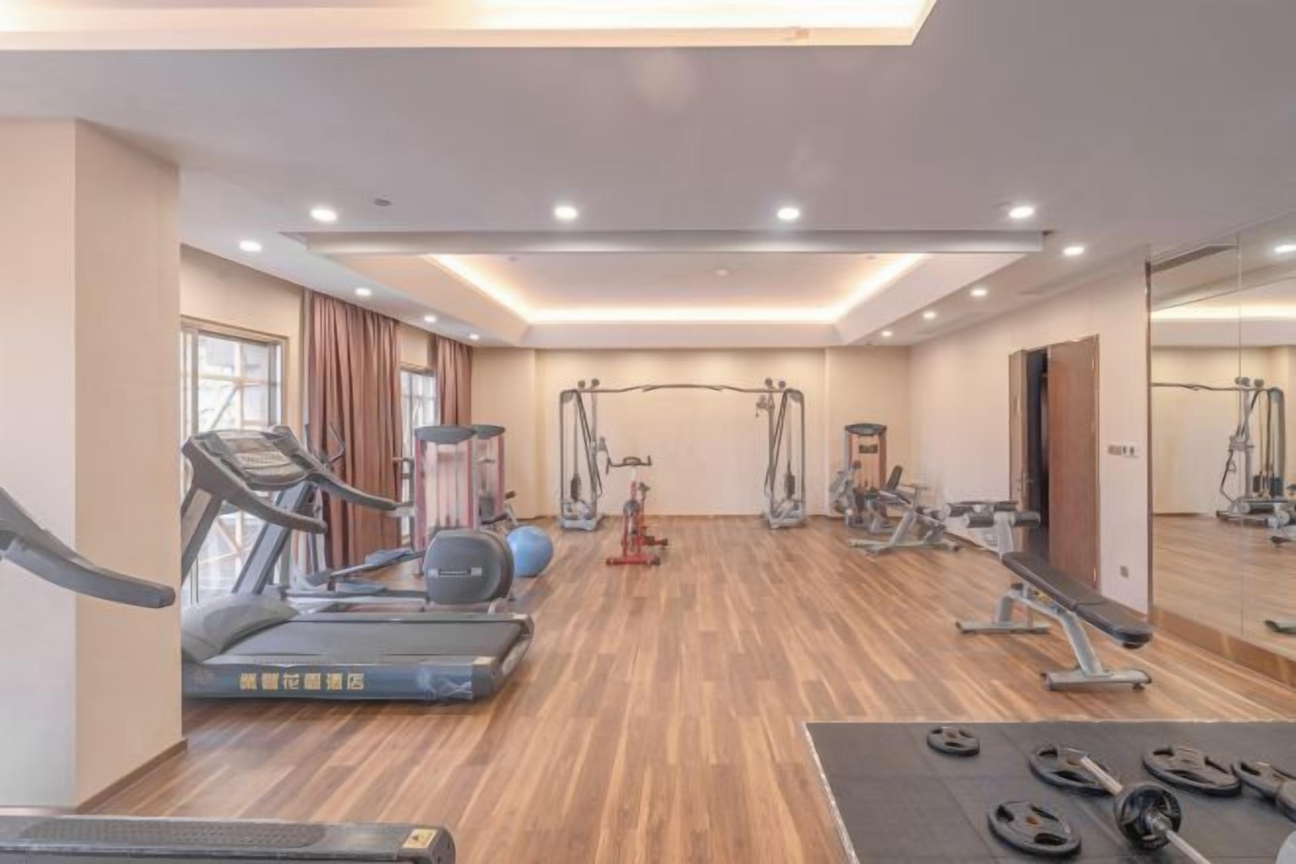 Ein Fitnessstudio mit Laufbändern, Crosstrainern und Gewichten.