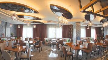 A spacious restaurant with multiple dining areas, including a central seating area and several smaller tables.