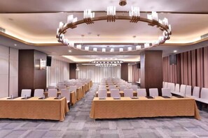 A conference room with rows of tables, chairs, and a large chandelier.