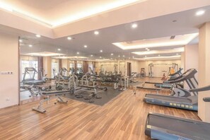 Un gimnasio amplio con diversos equipos de ejercicio, como cintas de correr, máquinas de pesas y pesas sueltas.