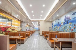 Un restaurant avec des banquettes et des tables, une fresque représentant une scène sous-marine, et un mur de verre sur un côté.