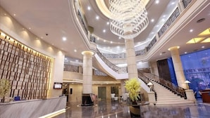 A spacious lobby with a grand staircase, multiple floors, and a modern chandelier. - Ye Feng Garden Hotel (Dongguan)