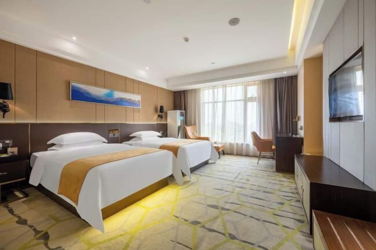 Une chambre d’hôtel avec deux lits, un bureau, une chaise et un téléviseur.