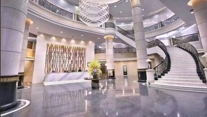 A spacious lobby with a grand chandelier, a central reception desk, and a spiral staircase. - Ye Feng Garden Hotel (Dongguan)