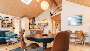 Een gezellige eethoek met een ronde tafel, houten stoelen en uitzicht op de keuken en woonkamer.
