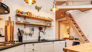 Een moderne keuken met witte kasten, houten planken en een ingebouwde vaatwasser.