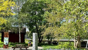 Un parc avec un pilier en pierre, une table de pique-nique et des bancs.