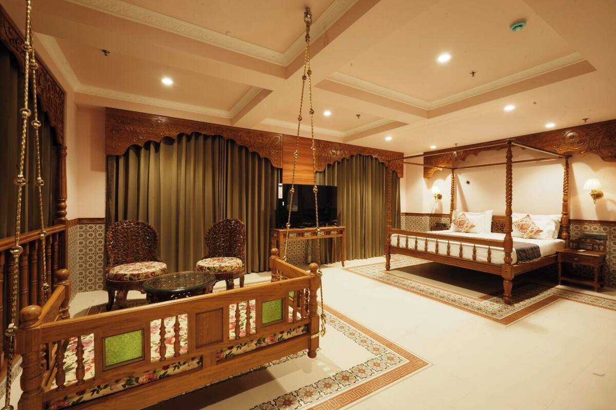A traditional room with a four-poster bed, a sofa with a glass table, and a television.