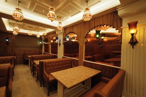 A restaurant with booths and tables, ornate chandeliers, and wooden paneling.