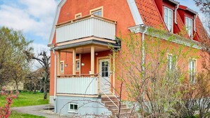 Punatiilinen talo, jossa on valkoinen parveke, pieni kuisti ja punainen katto.