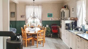Kodikas keittiö, jossa on ruokapöytä, tuoleja ja liesi.
