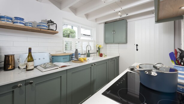A modern kitchen with grey cabinets, a white countertop, and a built-in oven.