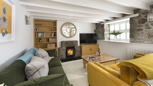 A cozy living room with a fireplace, a television, and a bookshelf.
