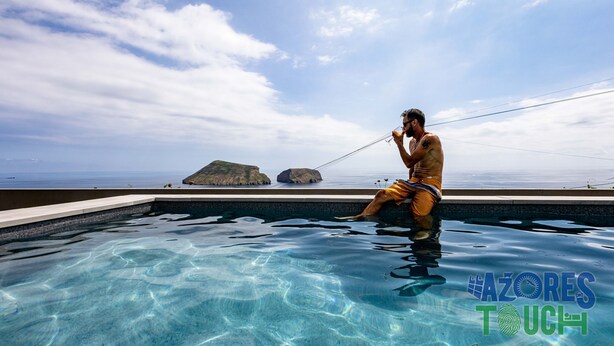 Ein Mann im Schwimmbecken mit Blick auf das Meer und Inseln.