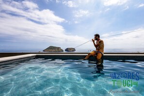A man in a swimming pool with a view of the sea and islands. - Casa dos Bastos in Feteira (Angra do Heroismo)