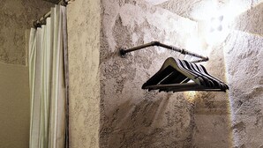 Een badkamer met douchegordijn, een ophangrek en een gestreepte tas op de vloer.