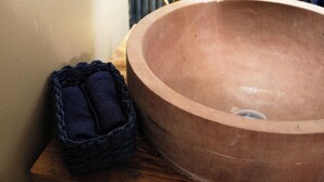 Un grand récipient rond, de couleur terre cuite, posé sur une surface en bois, accompagné d’un panier tissé bleu foncé.