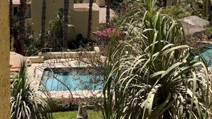 Un resort con piscina rodeada de palmeras y vista al océano.