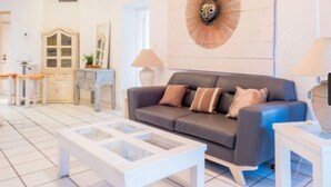 Una sala de estar moderna con un sofá gris, una mesa de centro blanca y un elemento decorativo en la pared.