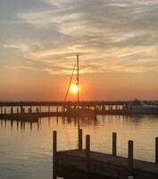 A pier extending into calm water with a sunset in the background.