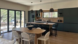 Une cuisine moderne dotée d’un îlot central, de meubles de couleur sombre et de luminaires suspendus.