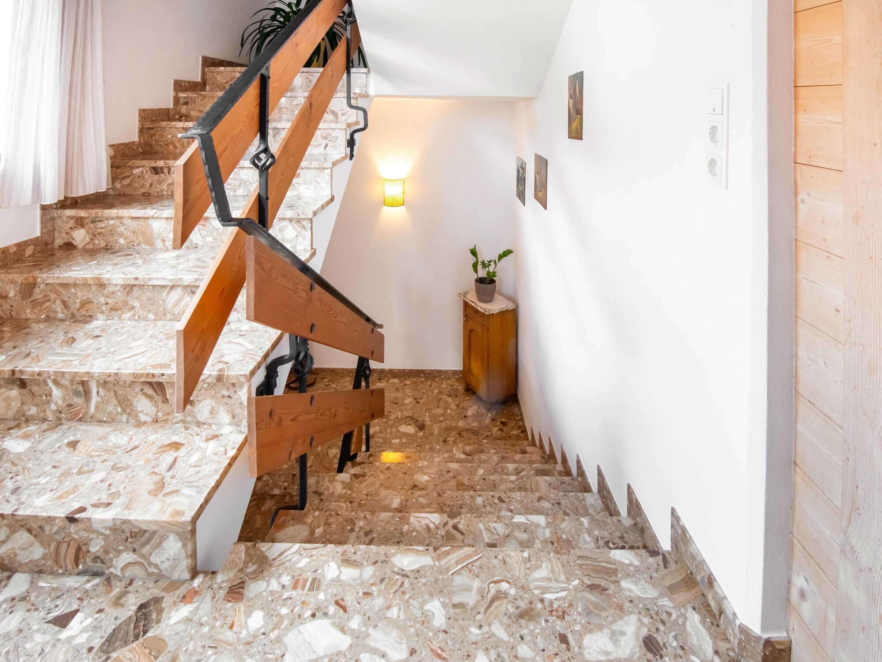 A staircase with a wooden handrail and a wall-mounted light fixture.