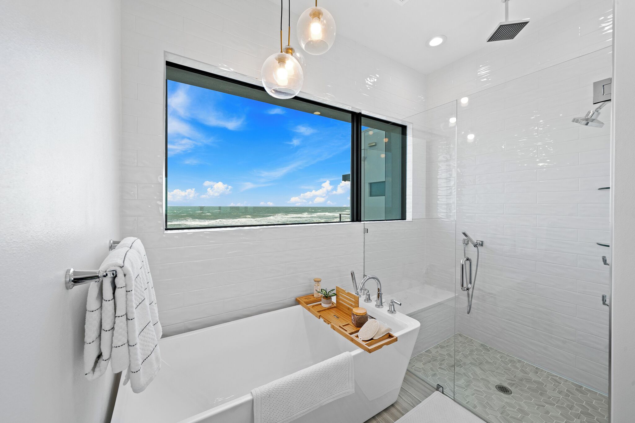 Une salle de bain moderne dotée d’une grande baignoire, d’une douche et d’une fenêtre donnant sur l’océan.
