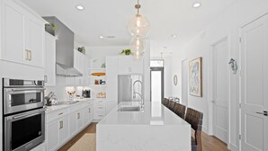 A modern kitchen with white cabinetry, stainless steel appliances, and a central island. - 4-bedroom oceanfront villa in Melbourne Beach with (Melbourne Beach)