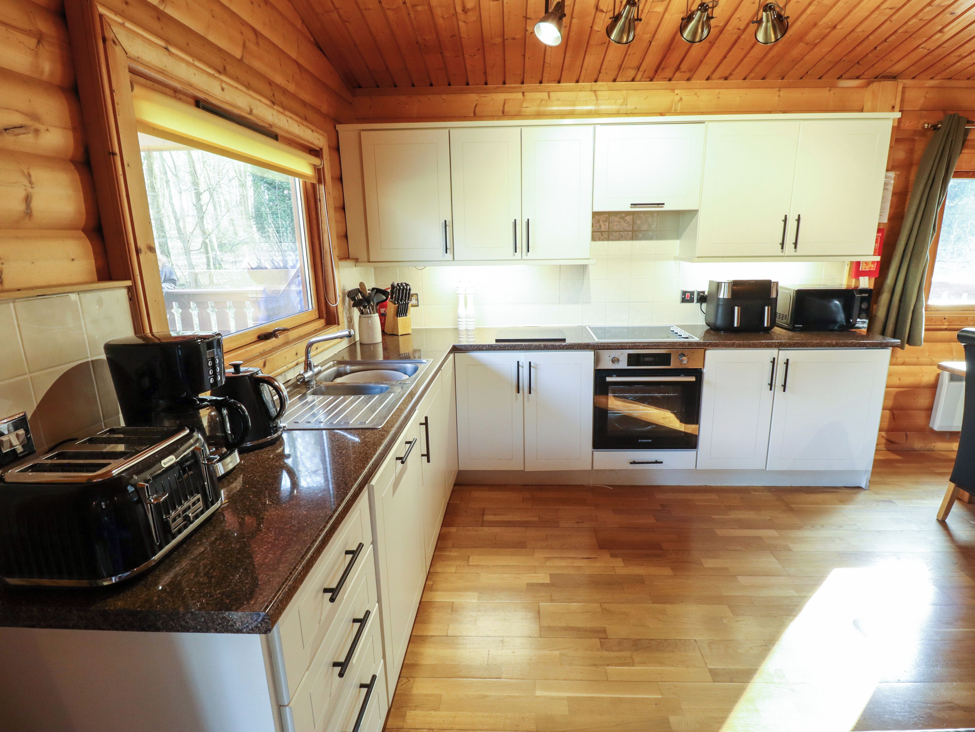 A modern kitchen with wooden cabinets, a built-in oven, a coffee maker, and a toaster.