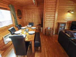 A wooden cabin with a dining area, a living room, and a bookshelf.