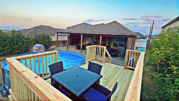 Ein Garten mit Swimmingpool, Holzterrasse und Gartenmöbeln.