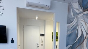 Una sala de estar moderna con un sofá gris, una almohada azul, un televisor plano montado en la pared y un cuadro abstracto grande.