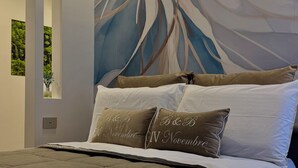 Un dormitorio con una cama grande, un mural abstracto moderno en la pared y una ventana con vistas a zonas verdes.