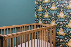 Ein Zimmer mit einem hölzernen Babybett an einer blumenmusterten Wand.