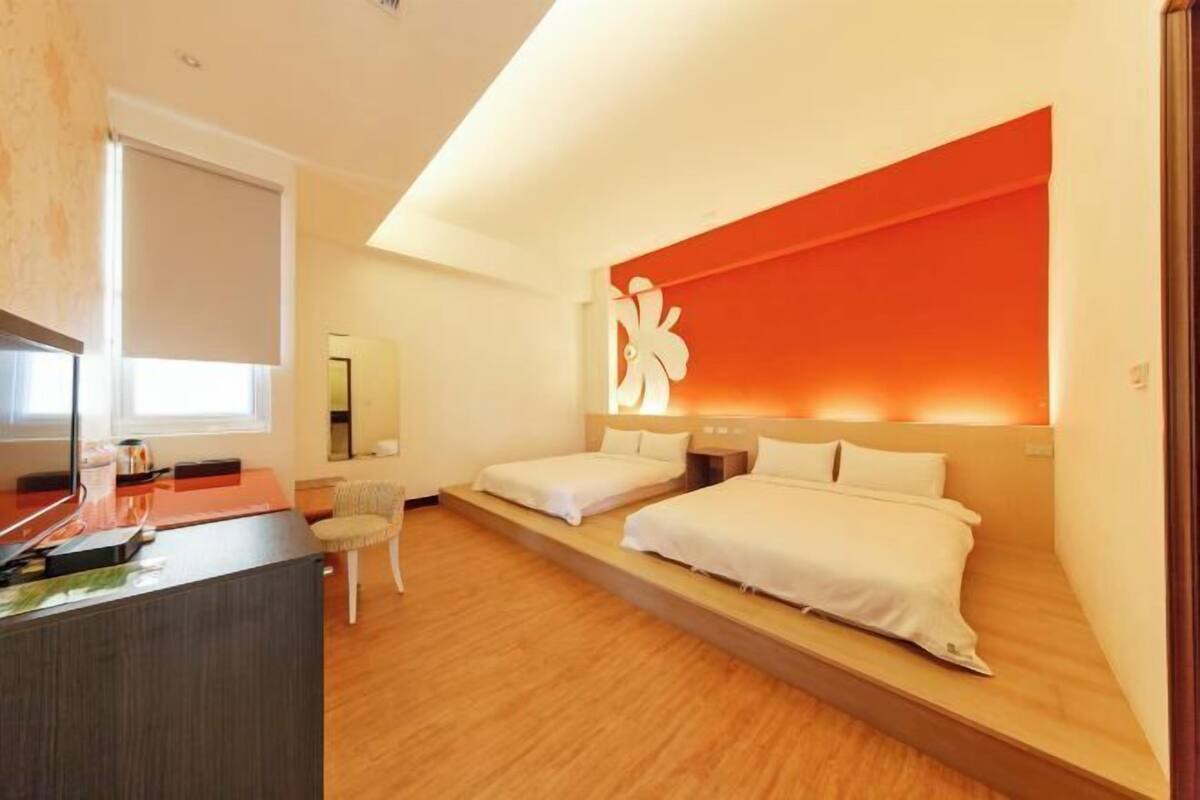 Une chambre d’hôtel avec deux lits, un bureau et une chaise.