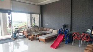 A spacious living area with a sofa, a coffee table, a red slide, and a dining area with red chairs. - Kenting Green Yard Hostel (Pingtung)