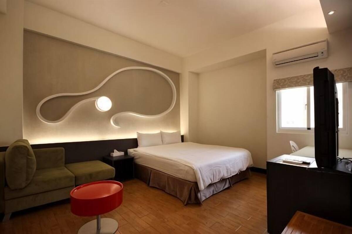 Une chambre d’hôtel moderne équipée d’un lit, d’un bureau, d’une chaise et d’un canapé.