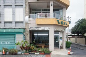 A two-story building with a balcony, a green awning, and potted plants in front. - Kenting Green Yard Hostel (Pingtung)
