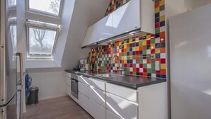 A modern kitchen with white cabinets, a colorful backsplash, a window, and a built-in oven. - 4 Star Holiday Home in Dybvad (Dybvad)