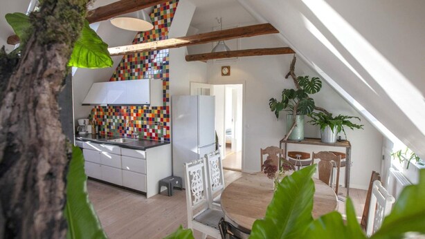 A modern kitchen with a colorful backsplash, wooden beams, and a dining area with a table and chairs. - 4 Star Holiday Home in Dybvad (Dybvad)