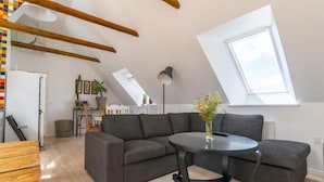 A modern loft apartment with a grey sectional sofa, a round black table, and a skylight. - 4 Star Holiday Home in Dybvad (Dybvad)